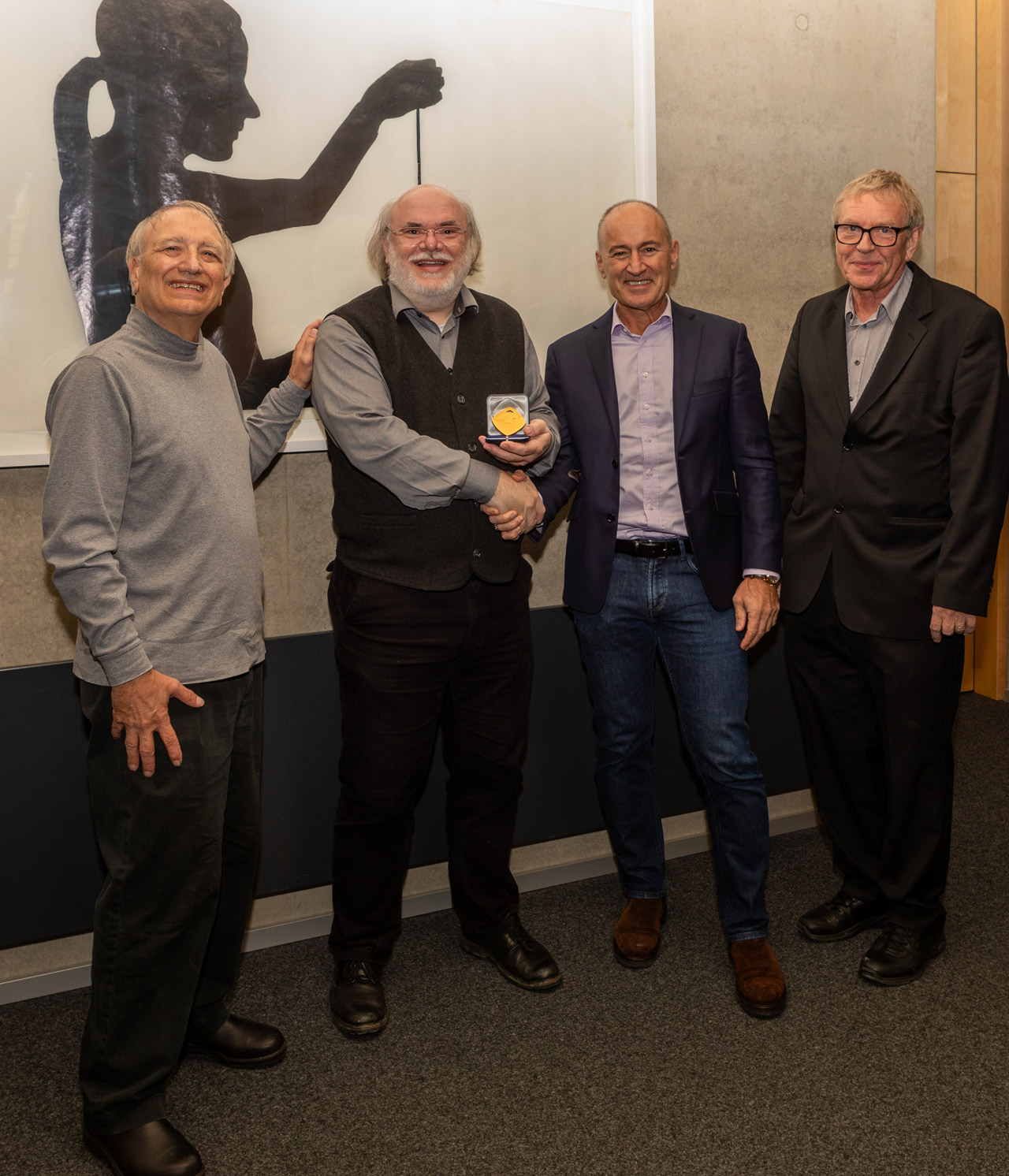 Photo showing Philipp Slusallek as he receives the EG Medal from Pat Hanrahan, Markus Gross, and Hans-Peter Seidel