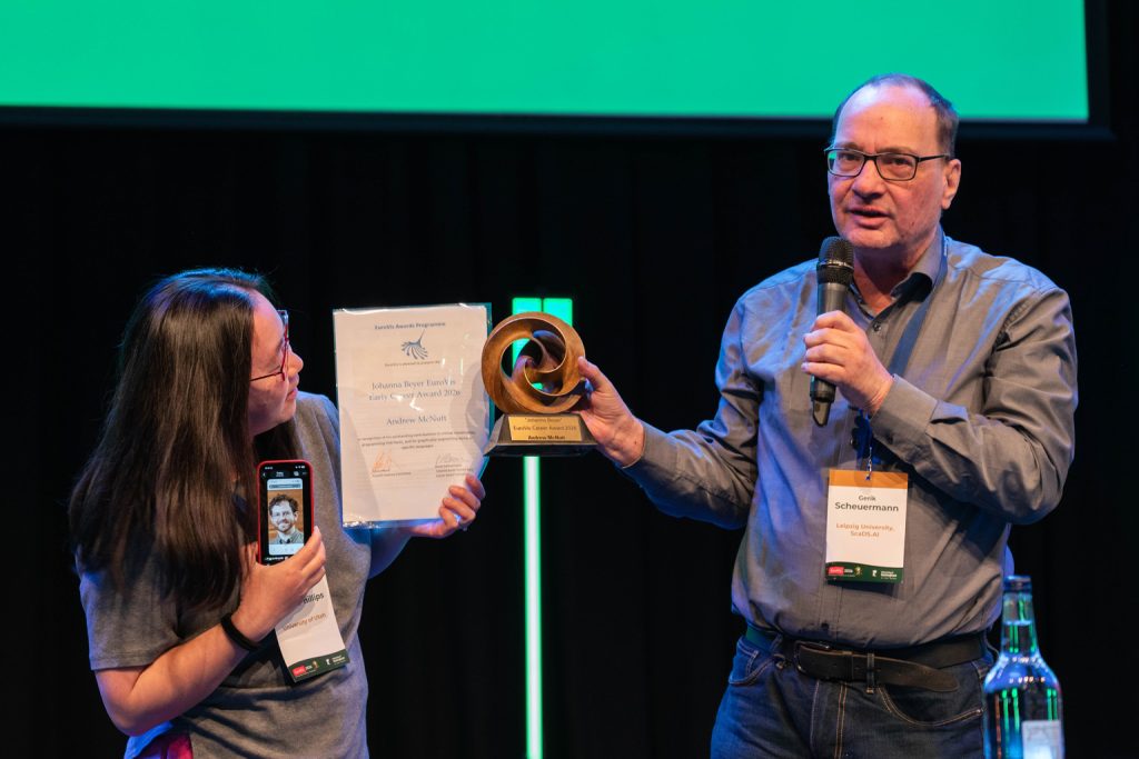 Bet Wang receiving the 2026 Johanna Beyer EuroVis Early Career Award on behalf of Andrew McNutt from chair Gerik Scheuermann