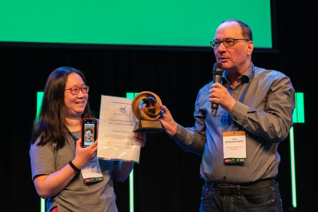 Bet Wang receiving the 2026 Johanna Beyer EuroVis Early Career Award on behalf of Andrew McNutt from chair Gerik Scheuermann